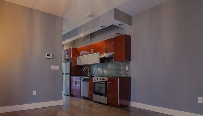 A kitchen with red cabinets and stainless steel appliances.