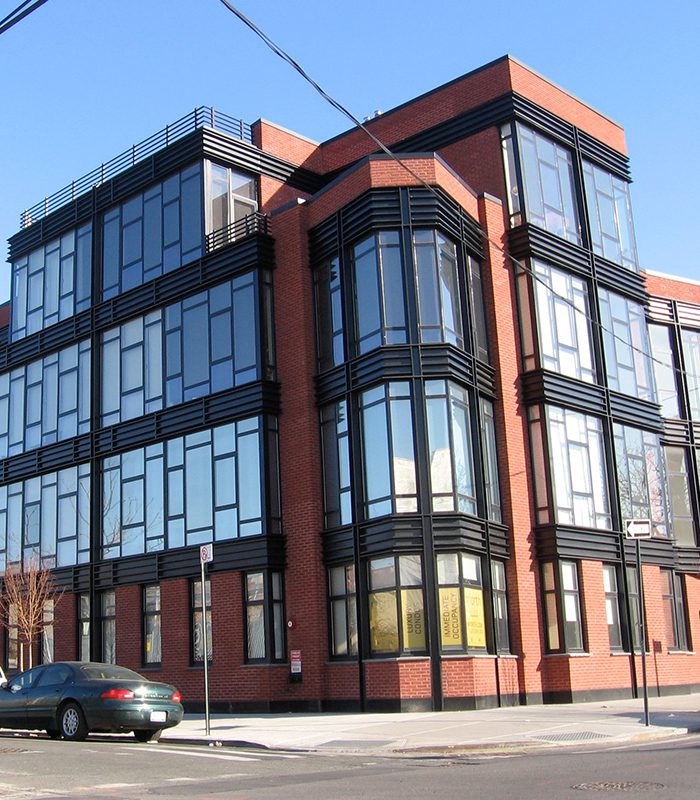 A building with many windows and cars parked on the side.