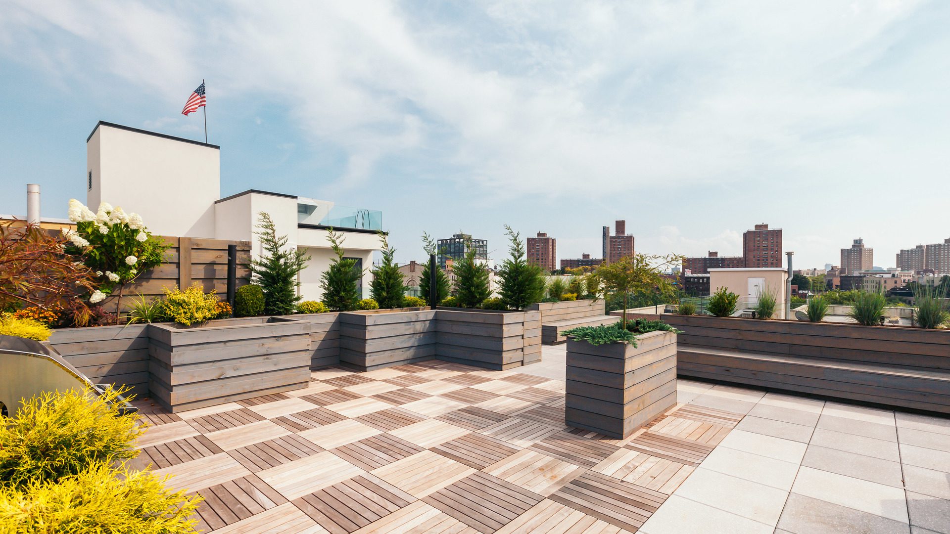 A rooftop garden with wooden planters and checkered tiles.