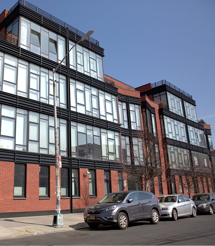 A building with many windows and cars parked on the side of it.