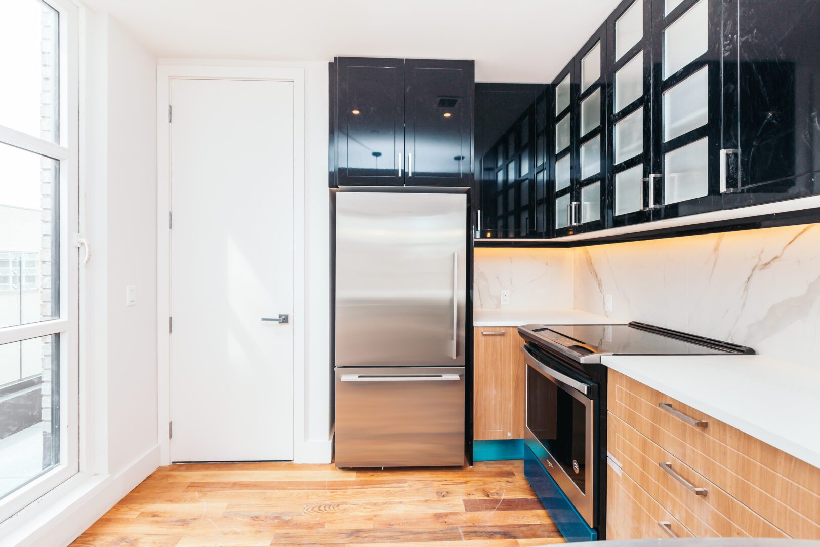 A kitchen with black cabinets and stainless steel refrigerator.