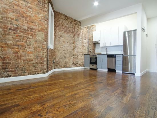 A kitchen with brick walls and wooden floors.